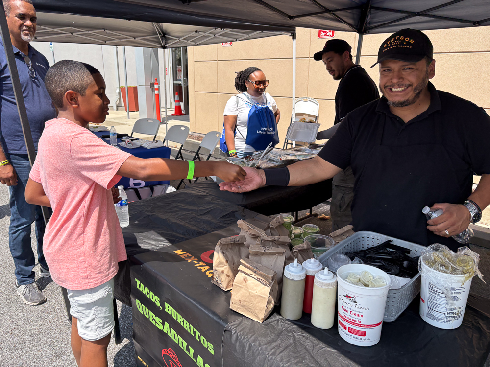 A man and boy at a food stand, exchanging Bredcoin for a birthday meal.